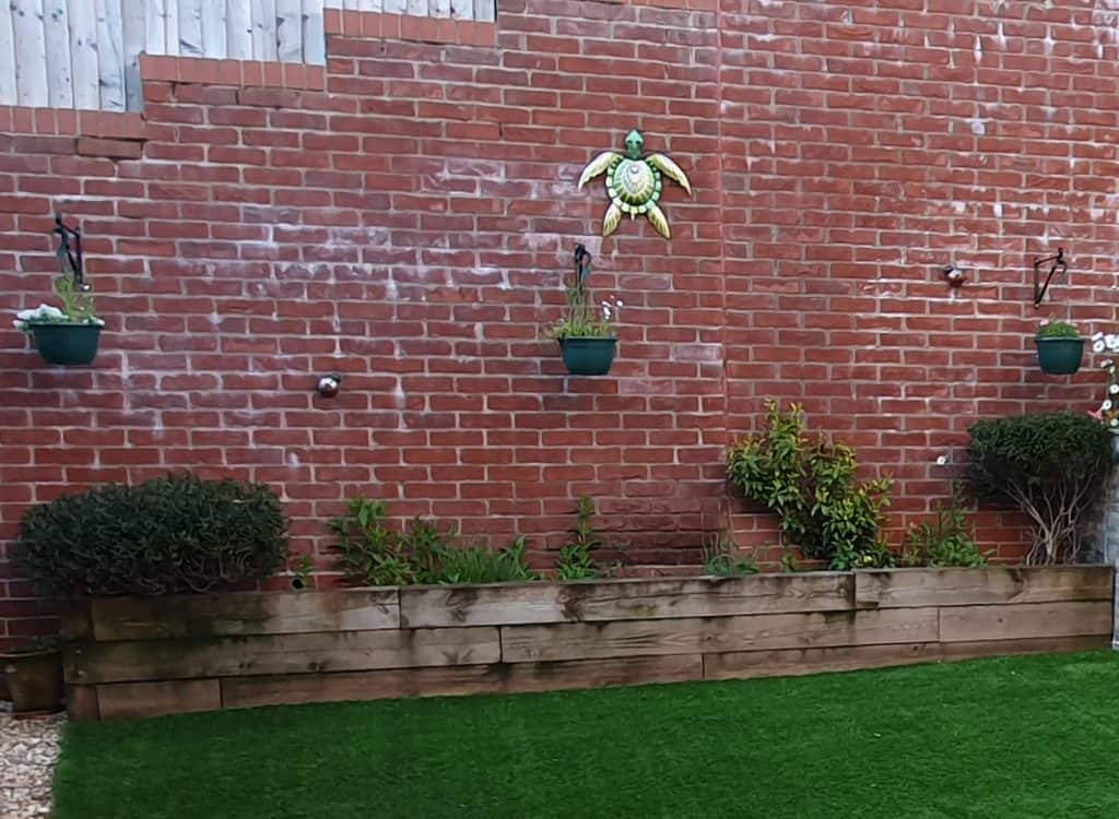 A backyard with hanging baskets and raised gardens