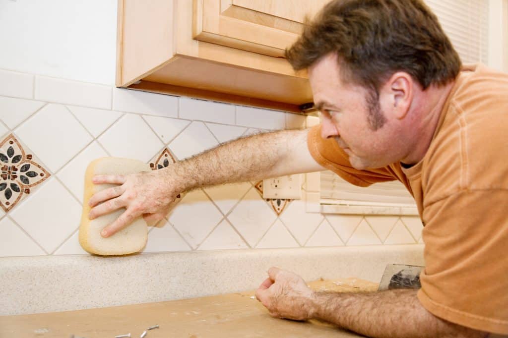 A tiler using a sponge for grouting and wiping water over tiles
