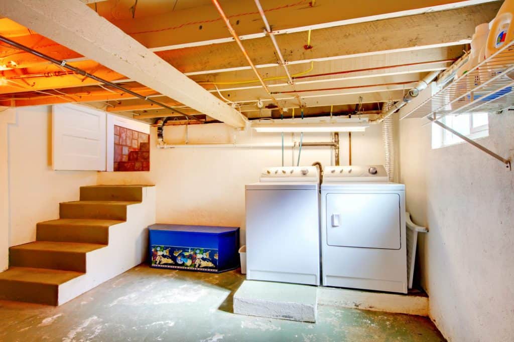 A basement with various exposed wires and pipes