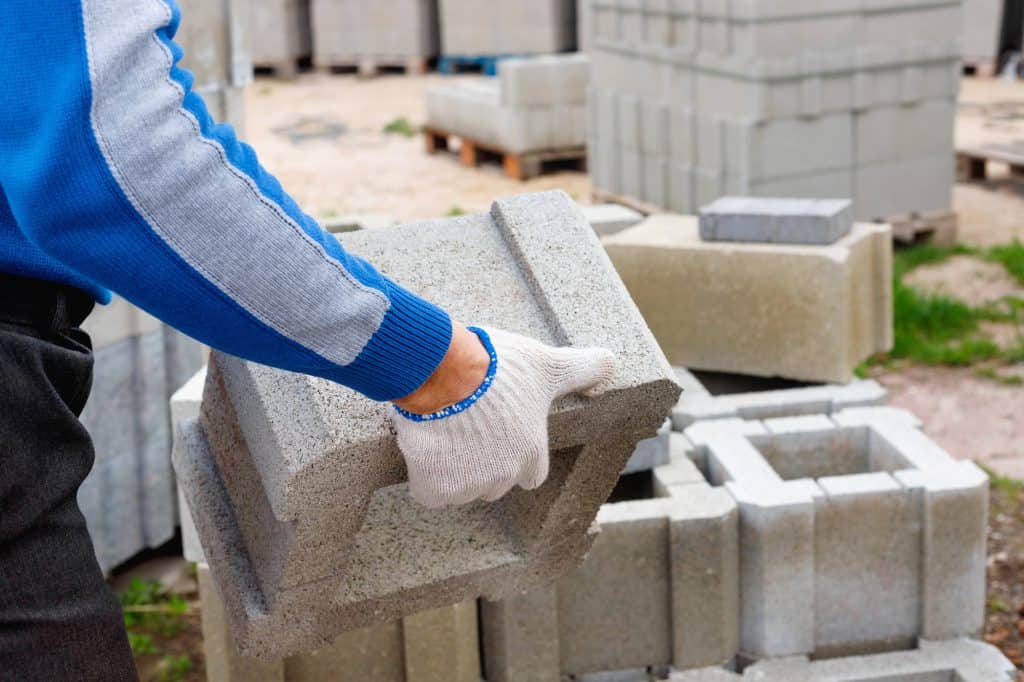 A cinder block being picked up by a construction worker