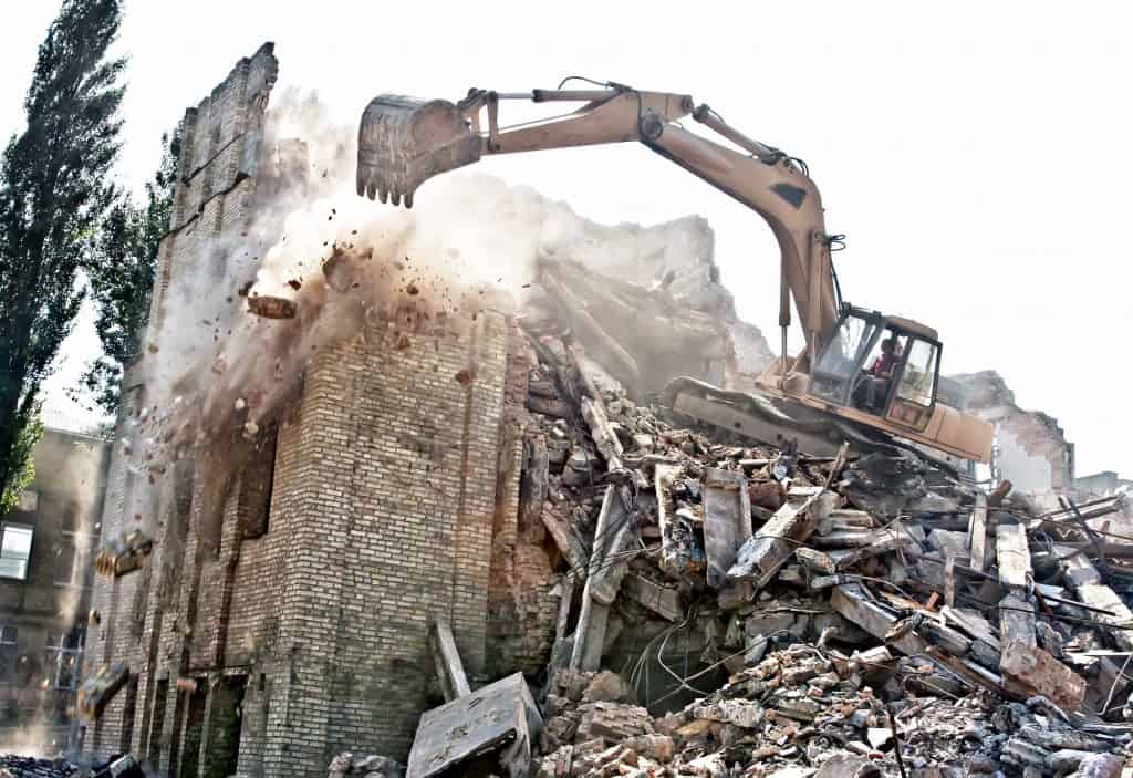 A digger excavator demolishing a building from a height