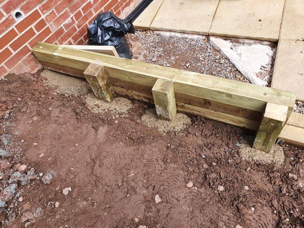A wooden retaining wall built from fencing posts