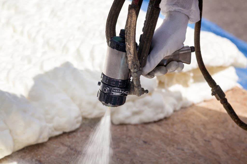 Spraying foam insulation into a ground area