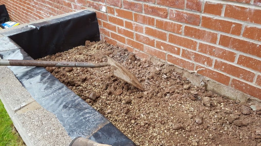 Topping up the flowerbed with a mix of soil and gravel for drainage