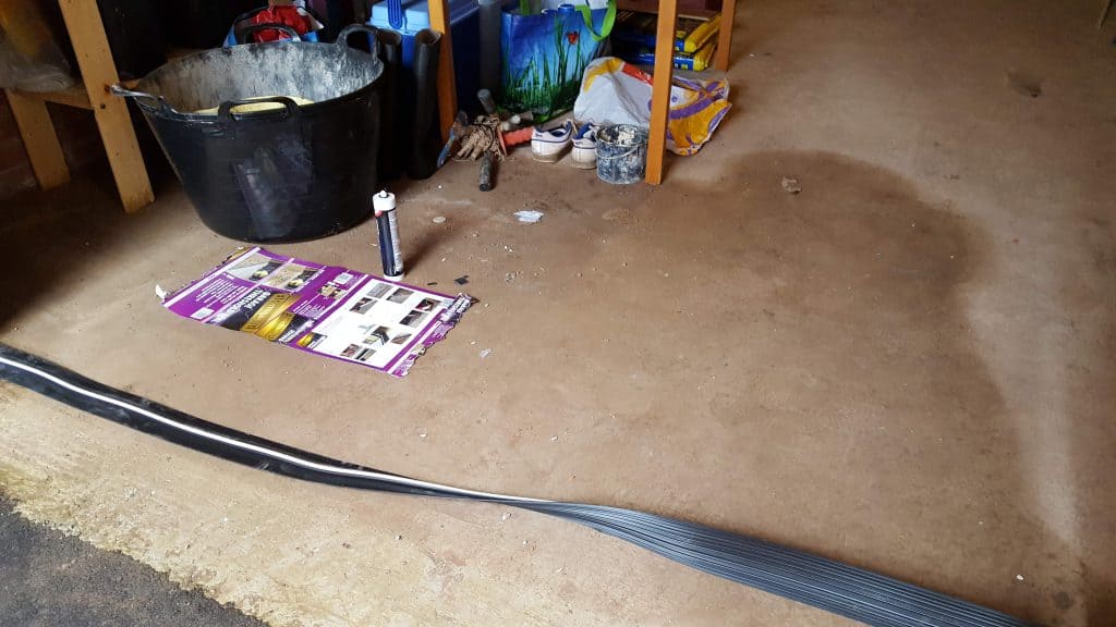 A weatherproof strip being installed along the garage door floor line