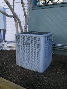 An outdoor AC air con unit sitting directly on the ground