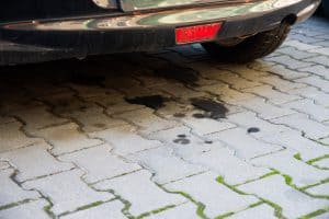 Oil leaking from an old car on a block driveway
