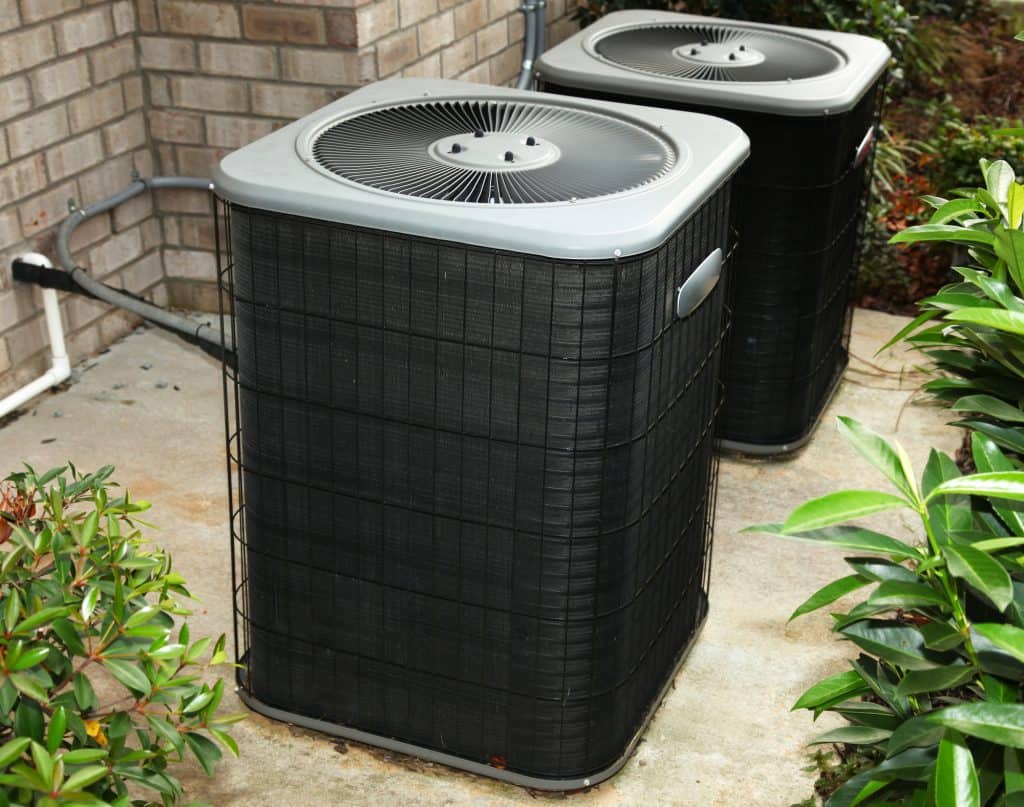 Two residential air conditioning AC units installed on a level outdoors