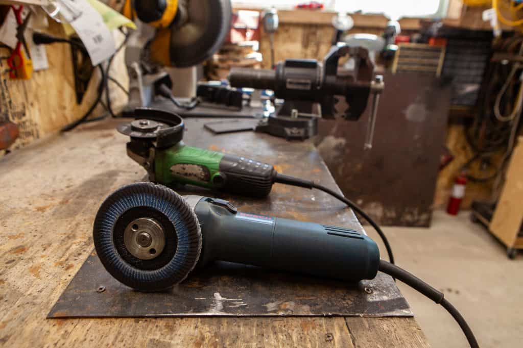 Two grinders including a surface grinder sitting on a workbench
